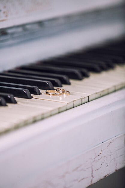 Фото Обручальные золотые кольца на белых клавишах пианино. церемония, религия, музыка, винтаж, обычай, украшение.