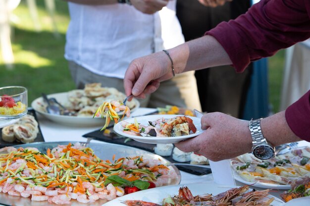 wedding guests serving themselves from a variety of dishes at outdoor buffet