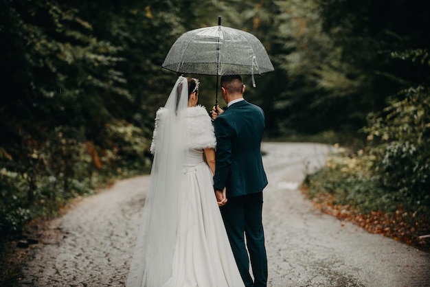 Wedding happy moments Happy young couple newlyweds walking the streets in rainy weather while carrying an umbrella