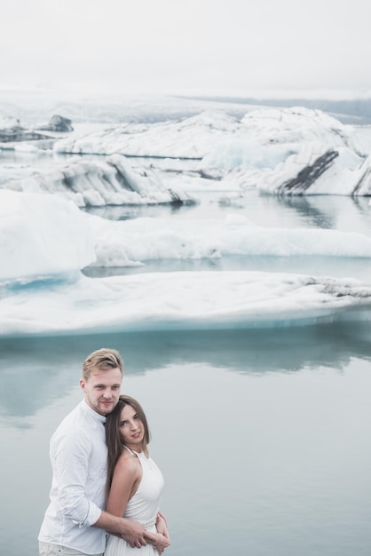 Wedding in Iceland. A guy and a girl in a white dress are hugging while standing on a blue ice