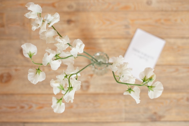 Photo wedding invitation birthday gift certificate for a spa or care decorated letter card on a white wooden table with a branch of white flowers.