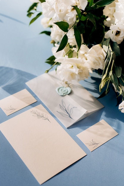 Photo wedding invitation in a blue envelope on a table with green sprigs