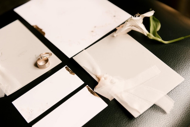 結婚式の招待状と指輪は白く、暗い背景に空きスペースがあります