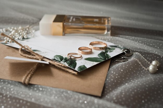 Photo wedding jewelry perfumes and envelopes with invitations on the table