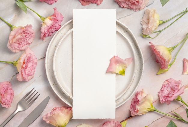 Wedding menu laying on a ceramic plate on a marble table decorated with flowers and ribbons