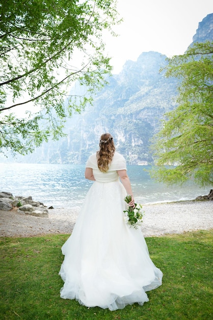 Wedding moment bride looking at lake Back view of a young amazing bride looking at the lake