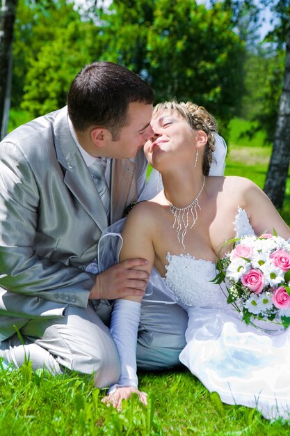 Foto la coppia di sposi si siede su un bacio d'erba