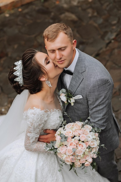 Wedding photo The bride in a voluminous white dress and a long veil stands with the groom in the park on a stone path View from above Portrait of the bride Beautiful curls Beautiful makeup