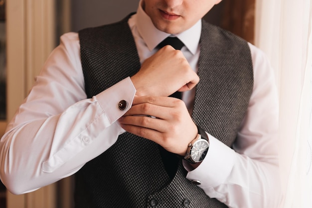 Wedding photo male groom fastens cufflinks on his shirt