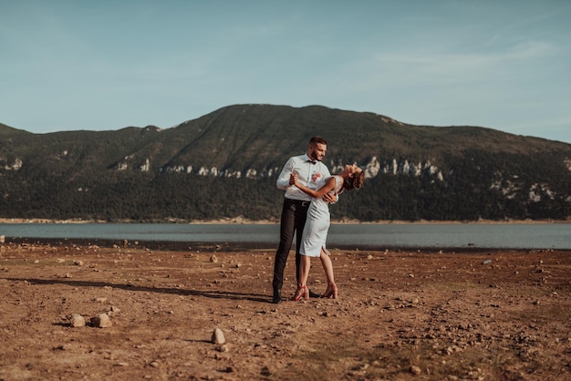 結婚式の写真。大きな湖のそばで楽しく踊る若い夫婦。限定フォーカス。高品質の写真