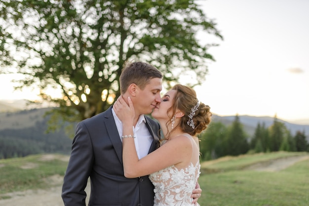 Wedding photography in the mountains. The newlyweds kiss. Close-up.