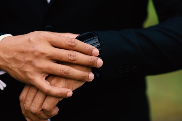 Wedding preparations mens watch in hand tidying clothes before ceremony