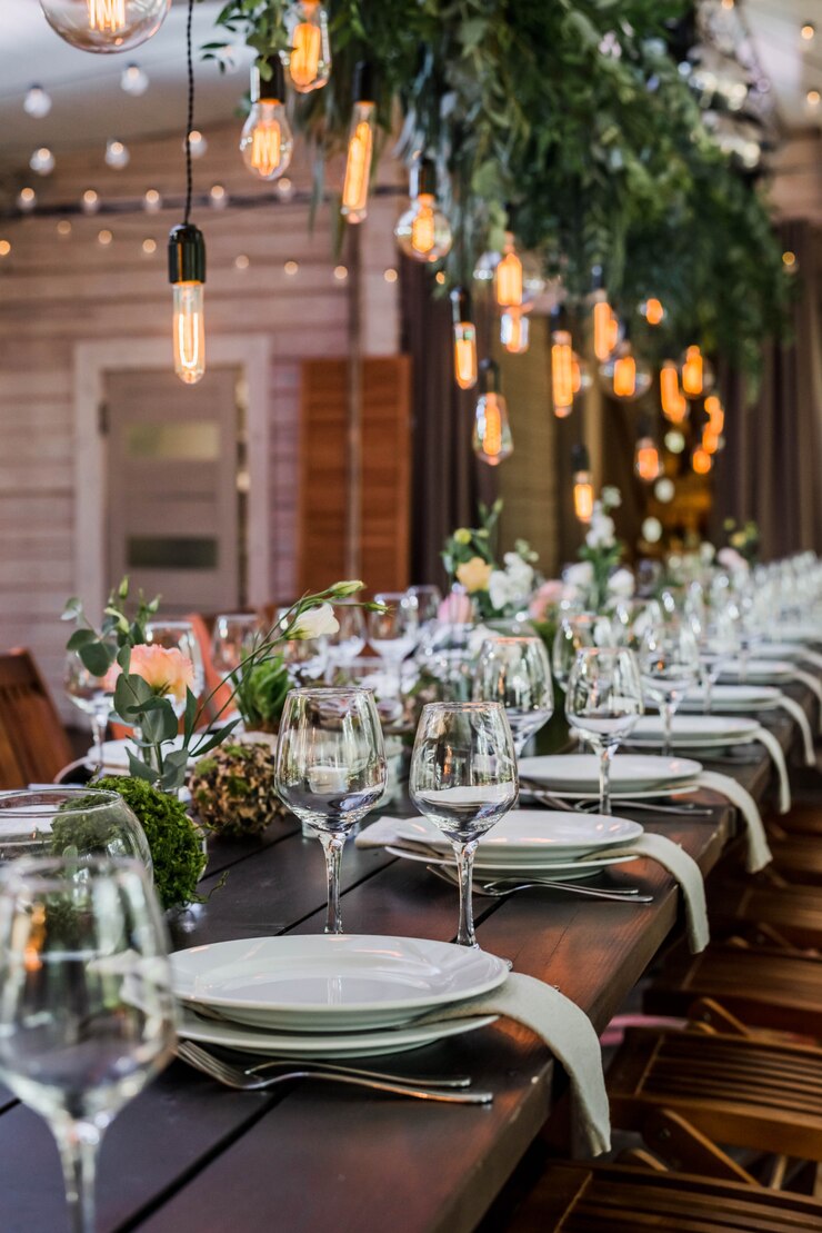 Photo wedding reception table with edison bulbs and decor of greenery.