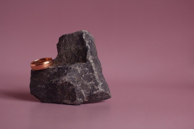 Wedding ring with a heartshaped stone on a pink background