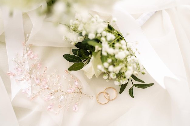 Photo wedding rings along with jewelry and a boutonniere on the veil