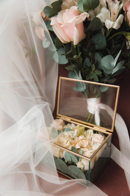 Wedding rings are in a golden decorative box with flowers