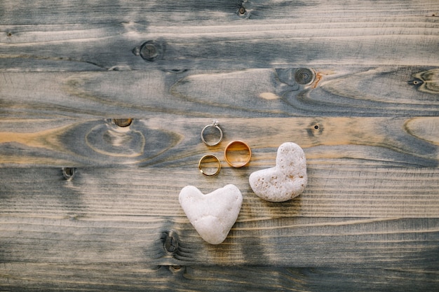 Fedi nuziali e anello nuziale in oro bianco su struttura in legno con pietre a forma di cuore