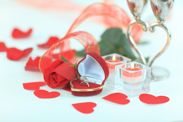 Wedding rings candles and rose on white background