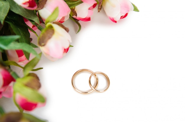 Wedding rings and flowers isolated on white background