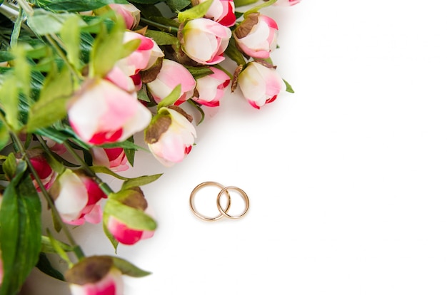 Wedding rings and flowers isolated on white background