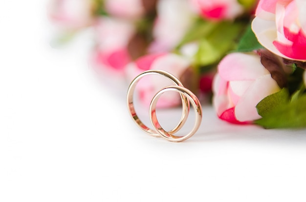 Wedding rings and flowers isolated on white  