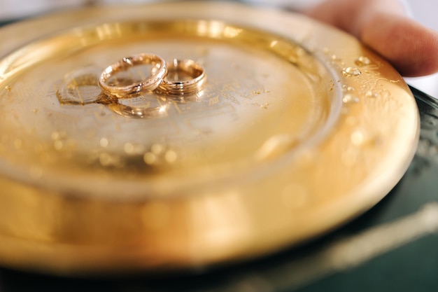 Wedding rings on golden platter in church