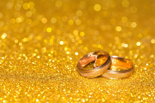 Wedding rings on a golden radiant background Glitter shine