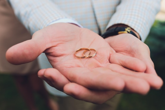 Photo wedding rings in the hand of the groom