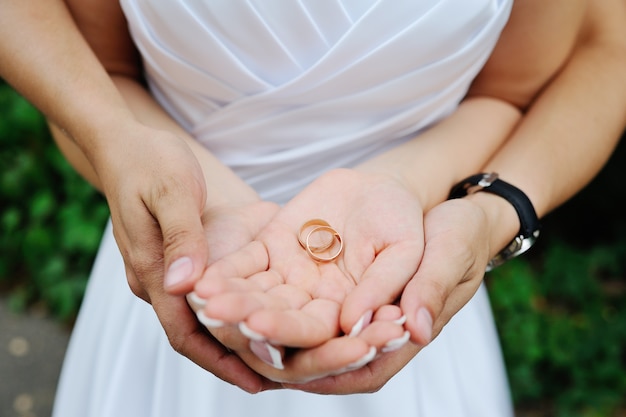 Wedding rings in hands of newlyweds