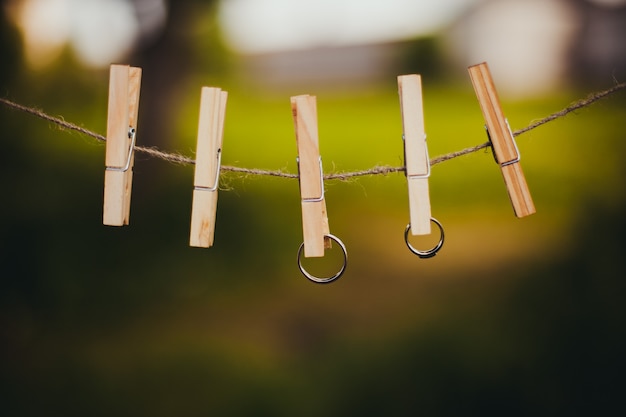 Wedding rings hang on clothespins on a background of green grass