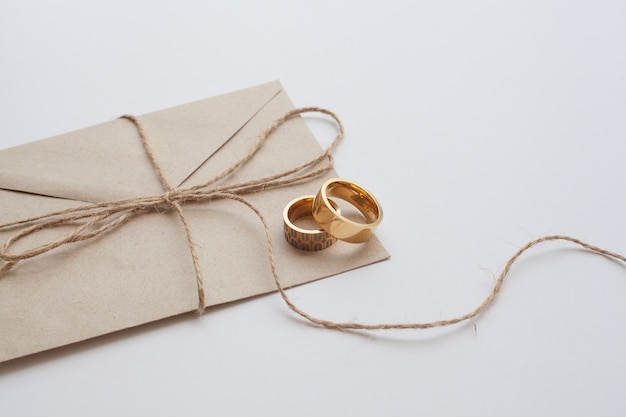 Wedding rings on invitation card with brown thread