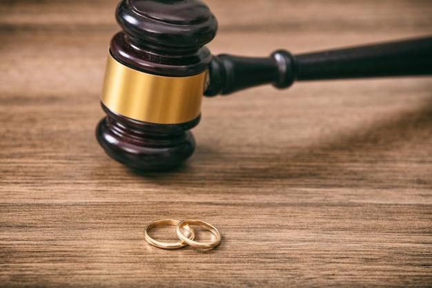 Wedding rings and judge gavel on wooden background copy space