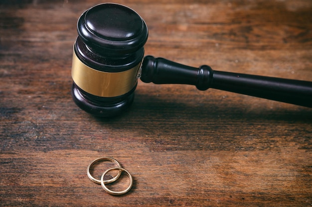 Photo wedding rings and judge gavel on wooden background copy space