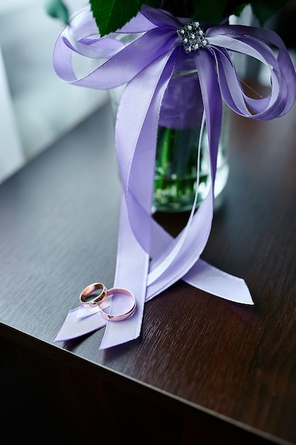 Wedding rings lie on a beautiful bouquet flowers with purple ribbons