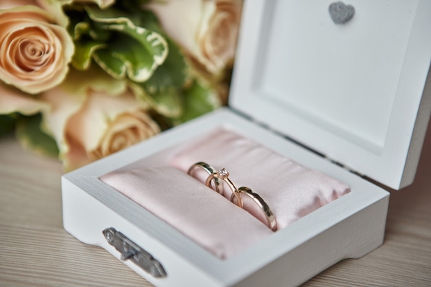 Wedding rings lie on a beautiful box with flowers as bridal accessories