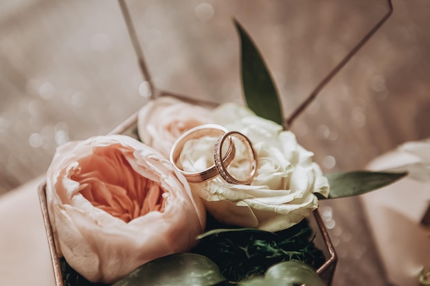 Wedding rings lie on a beautiful box with flowers as bridal accessories