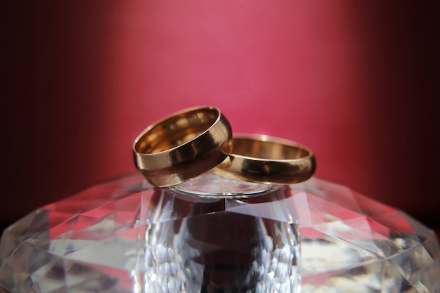 Wedding rings lie on a glass stand and on purple background