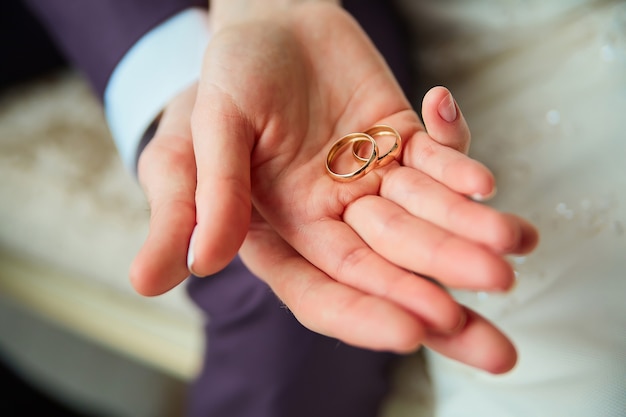 Wedding rings lie in palms of bride and groom