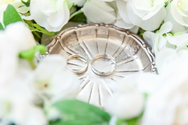 Wedding rings lie on wooden surface of bouquet of flowers