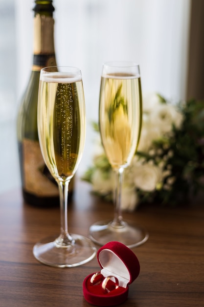 Photo wedding rings in a red box on the background of champagne glasses