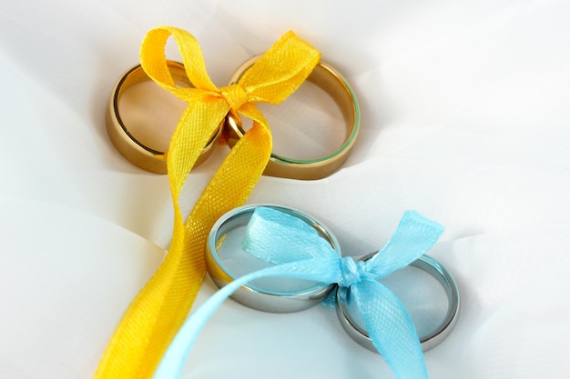 Wedding rings tied with ribbon on cloth background