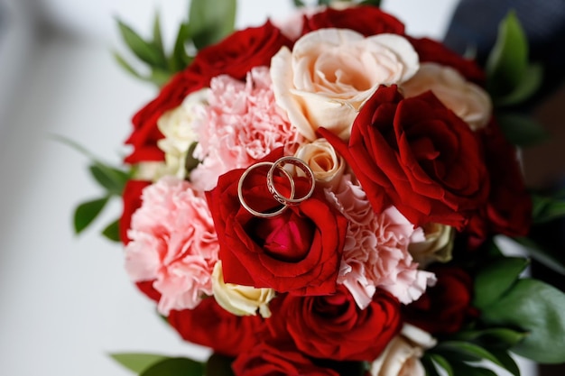 Photo wedding rings on a wedding bouquet of red and white roses.