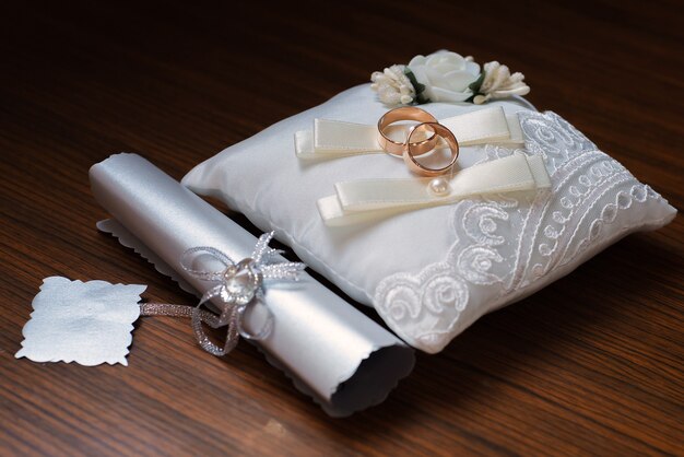 Photo wedding rings on white cushion with silver document