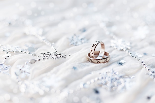 Wedding rings with sparkling silver snowflakes, christmas decorations. Symbol of wedding in winter time