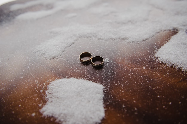 Wedding rings on a wooden background and snow