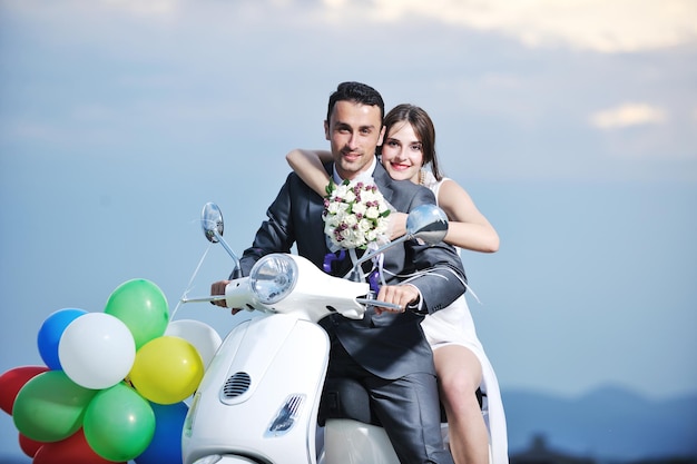 wedding sce of bride and groom just married couple on the beach ride white scooter and have fun