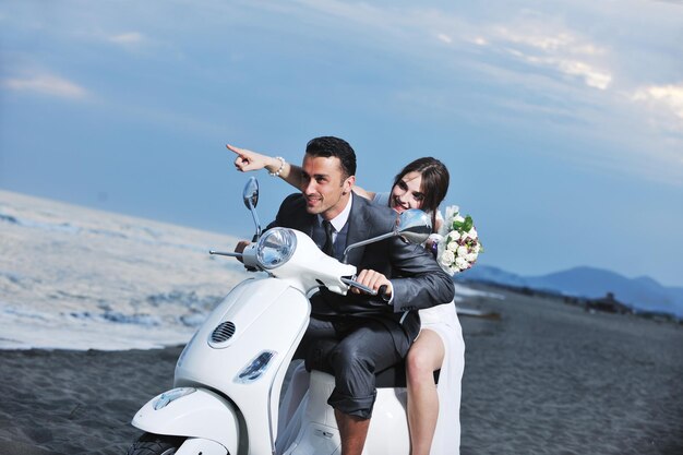 wedding sce of bride and groom just married couple on the beach ride white scooter and have fun