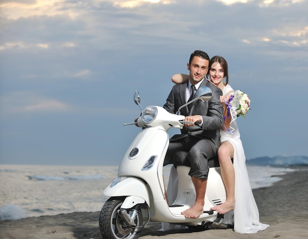 wedding sce of bride and groom just married couple on the beach ride white scooter and have fun