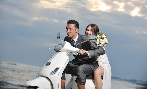 wedding sce of bride and groom just married couple on the beach ride white scooter and have fun