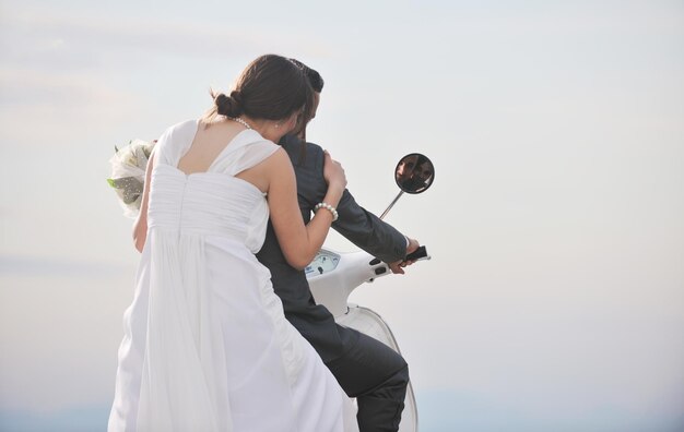 wedding sce of bride and groom just married couple on the beach ride white scooter and have fun